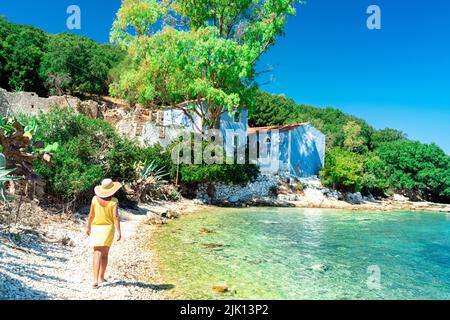 Donna che cammina su ciottoli bianchi di una spiaggia circondata da alberi, Porto Atheras, Cefalonia, Isole IONIE, Isole Greche, Grecia, Europa Foto Stock