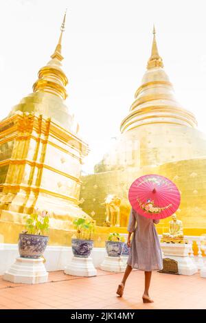 Donna con ombrello rosso a Wat Phra Singh Woramahawihan, Chiang mai, Thailandia, Sud-est asiatico, Asia Foto Stock