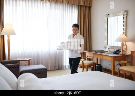 La cameriera vietnamita pullula biancheria e asciugamani in camera Foto Stock