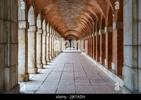 Grande corridoio esterno simmetrico con archi e colonne nel vecchio palazzo reale di Aranjuez. Madrid. Foto Stock