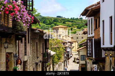 Vista prospettica delle case allineate in stretta strada della città vecchia e la chiesa sullo sfondo. Santillana del Mar, Santander. Foto Stock