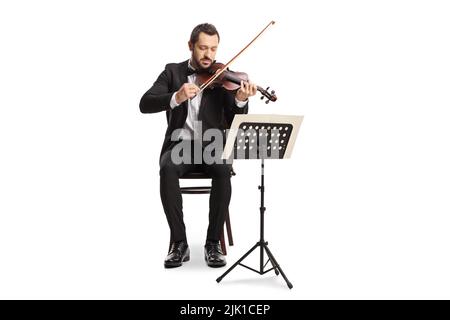 Ritratto a tutta lunghezza di un uomo elegante seduto e suona un violino con un supporto musicale isolato su sfondo bianco Foto Stock