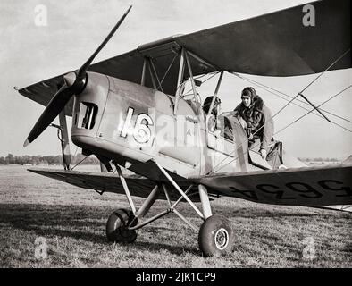 Un pilota tirocinante e il suo istruttore (nella cabina di pilotaggio anteriore) si preparano per un volo in una de Havilland Tiger Moth presso una Scuola elementare di addestramento al volo. La Tiger Moth era un biplano britannico del 1930s progettato da Geoffrey de Havilland e costruito dalla de Havilland Aircraft Company. È stato gestito dalla Royal Air Force (RAF) e da altri operatori come velivolo trainer primario Foto Stock