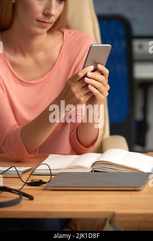 Immagine ritagliata di imprenditore femminile con smartphne nelle sue mani Foto Stock