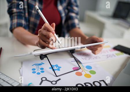 Primo piano di un grafico non riconoscibile utilizzando stilo e digitalizzatore mentre si lavora su un progetto promettente, sfondo sfocato Foto Stock