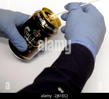 Un tecnico forense che preleva un campione di DNA da una lattina di birra. Foto Stock