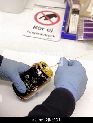 Un tecnico forense che preleva un campione di DNA da una lattina di birra. Foto Stock