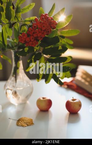 autunno ancora vita con rowan e mele su un tavolo in una casa accogliente interno. Foto Stock