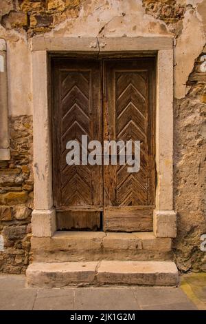 Un'antica porta di legno in un edificio in pietra nel centro medievale di Izola sulla costa slovena Foto Stock