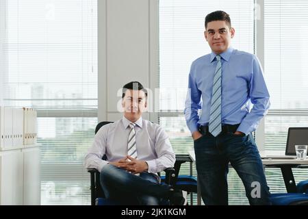 Gli uomini d'affari di mezza età Cheeful sorridono e guardano la macchina fotografica Foto Stock