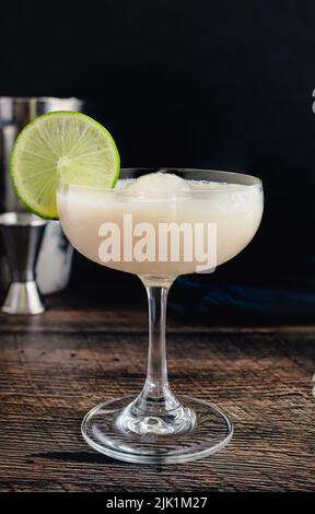 Gimlet di cioccolato bianco cocktail con sfera di ghiaccio: Cocktail fatto con gin, lime cordiale, e cioccolato bianco liquore in un bicchiere coupé Foto Stock