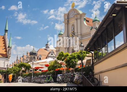 Monaco di Baviera, Germania - 6 luglio 2022: Al Rischart Cafe am Markt con vista sulla Heiliggeistkirche o la chiesa dello Spirito Santo nella città vecchia di Monaco Foto Stock