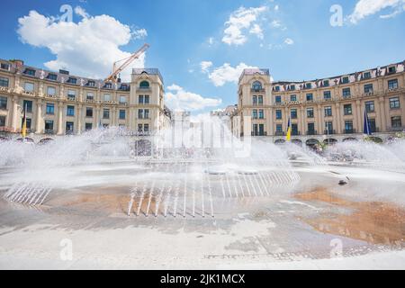 Monaco di Baviera, Germania - 6 luglio 2022: Lo Stachus o Karlsplatz nel centro di Monaco, con le sue acque opulente. Vista del Karlstor attraverso la f Foto Stock