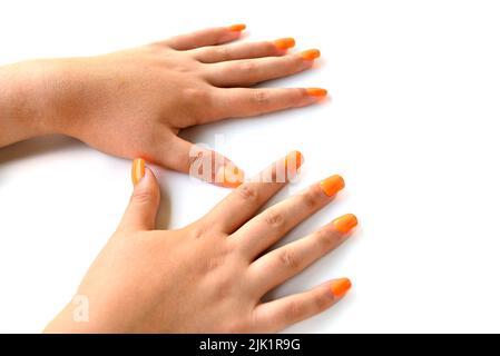 Le mani della ragazza con le unghie false arancioni. Manicure della donna Foto Stock