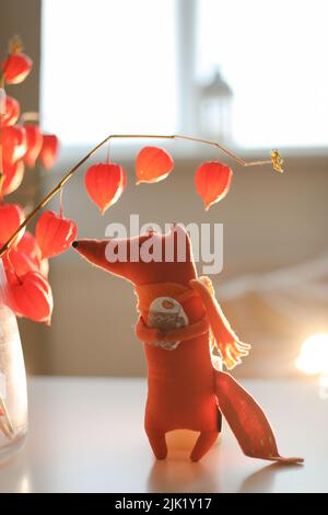 autunno natura morta con una volpe giocattolo, fiori, ramoscelli di physalis rosso in un vaso in una casa accogliente interno Foto Stock