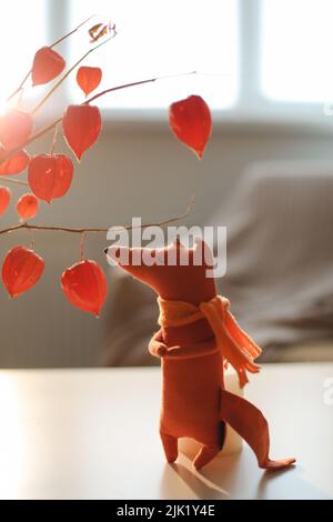 autunno natura morta con una volpe giocattolo, fiori, ramoscelli di physalis rosso in un vaso in una casa accogliente interno Foto Stock