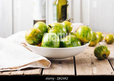 Una ciotola di pomodori verdi su un tavolo di legno. Foto Stock