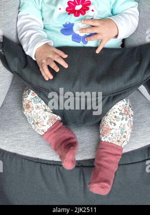 Gambe di una bambina neonato in un comodo sedile Foto Stock