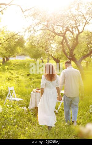 Bella coppia giovane in un luogo romantico, primavera fioritura melo frutteto. Felice coppia gioiosa godere l'un l'altro mentre cammina nel giardino. Uomo holdi Foto Stock