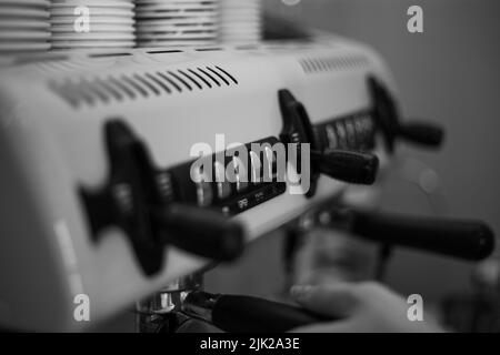 Il barista tiene in mano un portadocumenti e prepara il caffè con una macchina da caffè a doppia caldaia Foto Stock