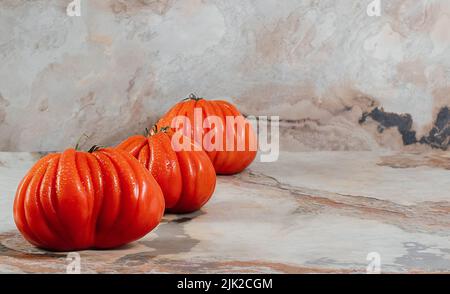Un gruppo di grossi pomodori Costoluto con origano su sfondo marrone, spazio per il testo Foto Stock