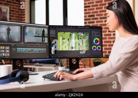 Editor grafico asiatico che lavora all'editing di filmati audio e video con software professionale per creare contenuti cinematografici per la post-produzione. Utilizzo del montaggio filmato per modificare un filmato multimediale. Foto Stock