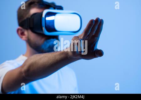 Uomo europeo in occhiali VR al neon. Concetto di gadget e tecnologie moderne. VR, AR, MR, XR- tecnologia futura. Foto Stock