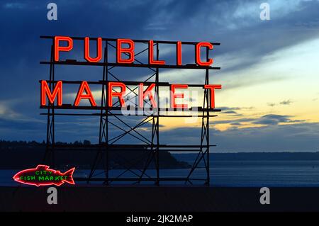 Il segnale al neon per il mercato pubblico di Seattle è illuminato al crepuscolo sulle rive del Puget Sound