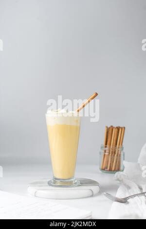 Latte di mango e panna montata e marshmallows in una tazza di vetro, latte d'arancia e panna, latte di frutta Foto Stock