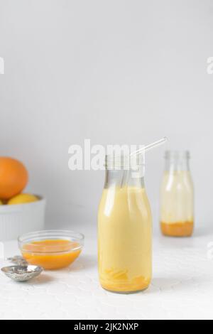 Latte di mango in una classica bottiglia di latte, purea di mango e latte intero in una bottiglia trasparente, milkshake di mango Foto Stock