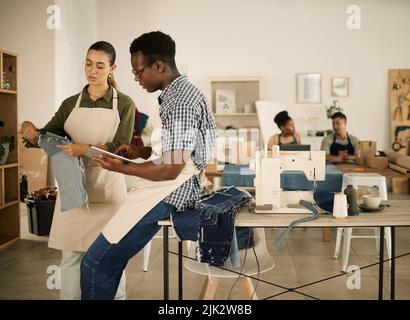 Abbigliamento, abbigliamento e stilisti che lavorano su nuovi design alla moda jean in un laboratorio di jeans. Persone ambiziose, giovani e creative in una startup Foto Stock