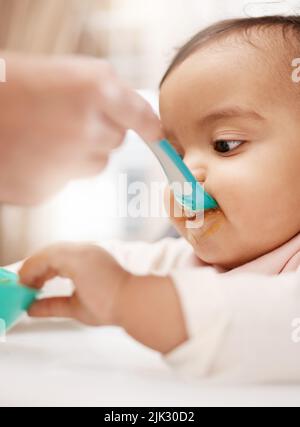 Hanno bisogno di tutta la nutrizione che possono ottenere. Una ragazza adorabile del bambino che mangia il suo alimento. Foto Stock