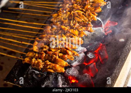 sate ayam o satay di pollo , o satay di pollo o carne con ingrediente di carbone sul fuoco rosso che grigliano da People. Satay tradizionale da, Indonesia Foto Stock