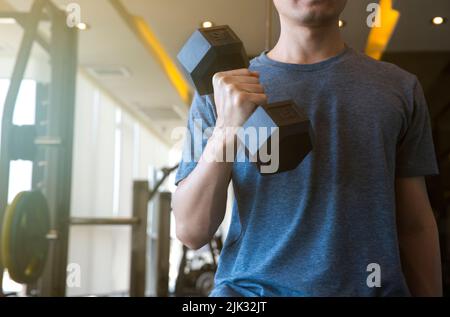 Giovane uomo principiante esercizio con i muscoli flessibili dumbbell in palestra, concetto di allenamento sportivo Foto Stock