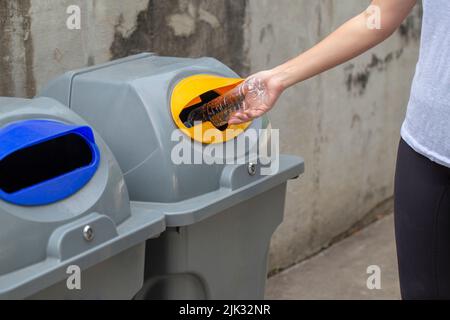 Primo piano donna gettando a mano vuota bottiglia di plastica goccia nel cestino di riciclaggio , salvare il concetto di mondo Foto Stock