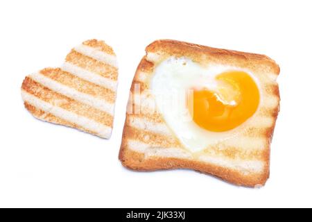 Uova fritte a forma di cuore in un pane tostato con segni di griglia isolato su sfondo bianco Foto Stock