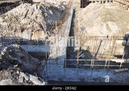 Primo piano di un basamento in calcestruzzo, costruzione di fondamenta di case in cemento con barre di rinforzo in acciaio. Foto Stock