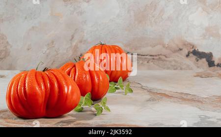 Un gruppo di grossi pomodori Costoluto con origano su sfondo marrone, spazio per il testo Foto Stock