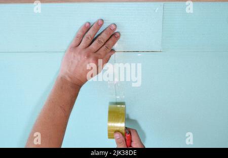 Installazione di sottostrati insonorizzanti, isolamento acustico su un pavimento prima di pavimenti in legno duro, installazione di pavimenti in legno laminato. Foto Stock