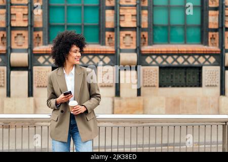 donna sorride felice con un cellulare in mano Foto Stock