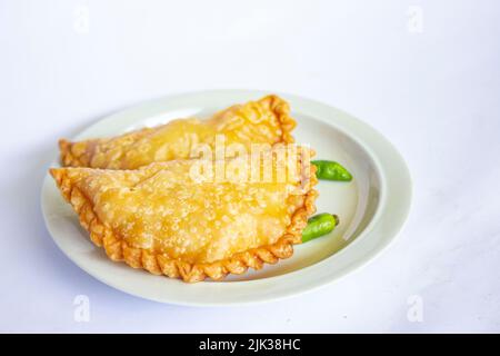 torta di pastie o torta di pasticceria o pastello kue servito con peperoncino verde in un piccolo piatto su sfondo di legno. torta pastello indonesiana Foto Stock