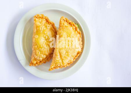 torta di pastie o torta di pasticceria o pastello kue servito con peperoncino verde in un piccolo piatto su sfondo di legno. torta pastello indonesiana Foto Stock