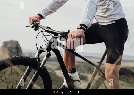 Cropped irriconoscibile professionista maschile ciclista seduto sulla sua bici all'aperto, Sportsman Riding su Trail Track Foto Stock