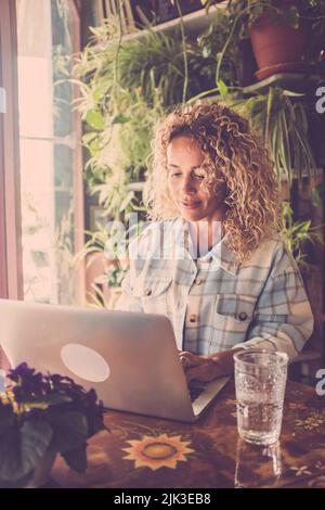 Concetto di persone che lavorano online con un notebook in un ambiente di lavoro domestico alternativo. Giovane donna godere e gestire il suo web business internet con un compu Foto Stock