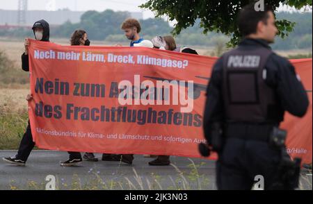 Schkeuditz, Germania. 30th luglio 2022. I partecipanti a una dimostrazione portano con sé una scritta "No all'espansione dell'aeroporto cargo" vicino all'aeroporto di Lipsia-Halle. Circa 250 attivisti ambientali protestano contro la prevista espansione del centro merci. Credit: Sebastian Willnow/dpa/Alamy Live News Foto Stock