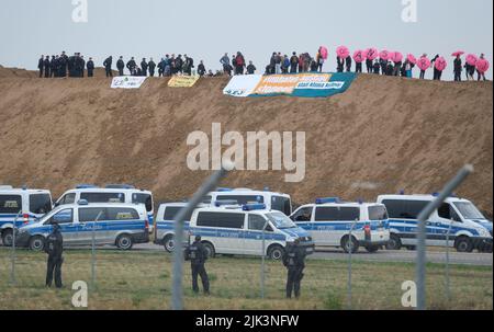 Schkeuditz, Germania. 30th luglio 2022. Gli attivisti climatici hanno occupato una collina sul sito di costruzione della società di logistica DHL presso l'aeroporto di Lipsia-Halle e stanno tenendo in mano lo slogan 'Transform LEJ' utilizzando ombrelloni. L'azione ha lo scopo di protestare contro la prevista espansione del mozzo aereo cargo. Credit: Sebastian Willnow/dpa/Alamy Live News Foto Stock