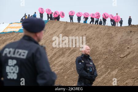 Schkeuditz, Germania. 30th luglio 2022. Gli attivisti climatici hanno occupato una collina sul sito di costruzione della società di logistica DHL presso l'aeroporto di Lipsia-Halle e hanno la scritta 'Transform LEJ' per mezzo di ombrelloni. L'azione dell'alleanza 'Transformation LEJ' è quella di protestare contro l'espansione pianificata del mozzo aereo cargo. Credit: Sebastian Willnow/dpa/Alamy Live News Foto Stock