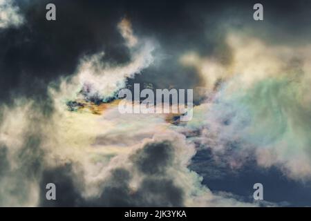 Diffrazione di luce su gocce di acqua sovraraffreddata nelle nuvole, nubi arcobaleno contro il cielo blu in condizioni di sole chiaro, iridazione di nubi di cumulo Foto Stock