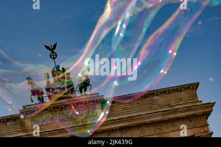 Berlino, Germania. 30th luglio 2022. Un artista di strada attinge bolle di sapone di grandi dimensioni nel cielo di fronte alla porta di Brandeburgo. Credit: Paul Zinken/dpa/Alamy Live News Foto Stock