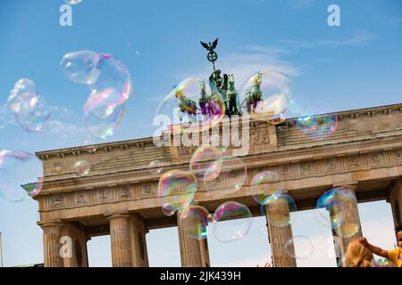 Berlino, Germania. 30th luglio 2022. Un artista di strada attinge bolle di sapone di grandi dimensioni nel cielo di fronte alla porta di Brandeburgo. Credit: Paul Zinken/dpa/Alamy Live News Foto Stock